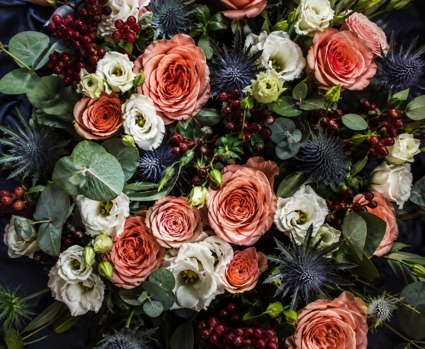 Dichter Strauß aus lachsfarbenen Rosen und Disteln von oben